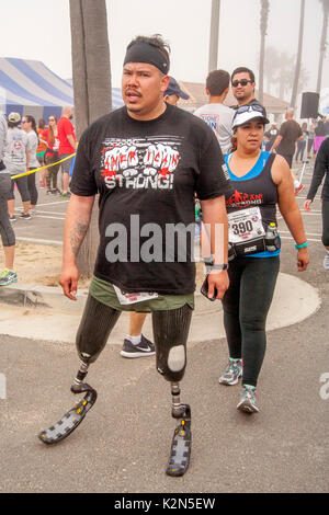 A proud Hispanic double amputee wearing prosthetic knees and feet catches his breath after crossing the finish line at a community foot race in Huntington Beach, CA. Stock Photo
