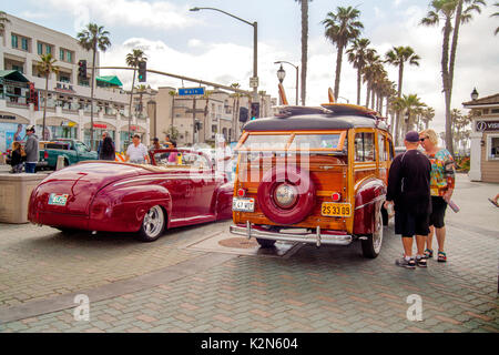 A 1947 Ford convertible and 1947 Ford Super Deluxe 'woodie' station wagon are on display at a classic car show in downtown Huntington Beach, CA.  Note  surfboards on roof, antique license plate and palm trees. Stock Photo