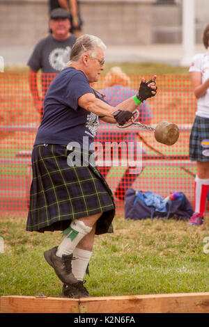 A hefty senior woman wears a tartan kilt as she whirls to throw the hammer at a Scottish festival in Costa Mesa, CA. Stock Photo