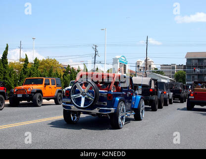 OCEAN CITY, MD - AUGUST 26, 2017: A pair of hands holding a cellphone takes a mobile photo from out of the top of an open vintage jeep waiting at a tr Stock Photo