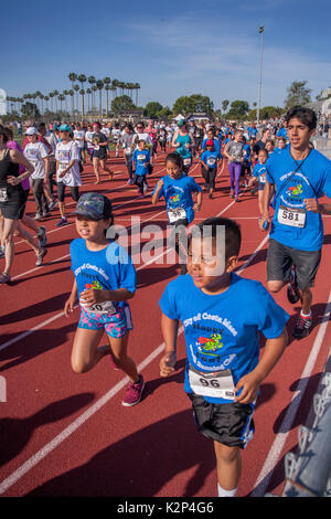 Young Hispanic athletes pound down the running track at a holiday foot race in Costa Mesa, CA. Stock Photo
