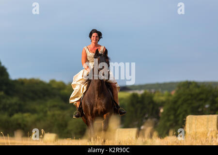 mature woman riding an Andalusian horse in the field Stock Photo
