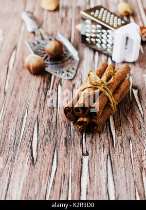 Bundle of cinnamon with nuts and flowers on the wooden table, selective focus Stock Photo