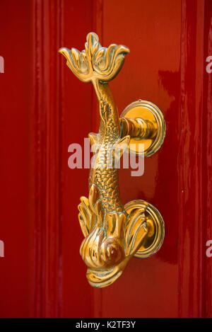 Close-up view of the fish shaped golden knocker on a red wooden door. Valetta, Malta Stock Photo