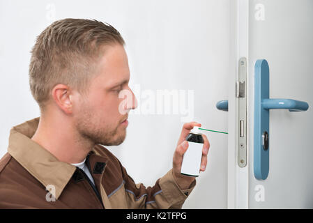 Close-up Of Young Male Carpenter Lubricating Door With Oil Stock Photo