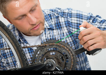 Close-up Of Young Man Oiling Bicycle Chain Stock Photo