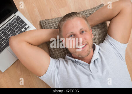 Young Happy Man Lying On Floor With Laptop Stock Photo