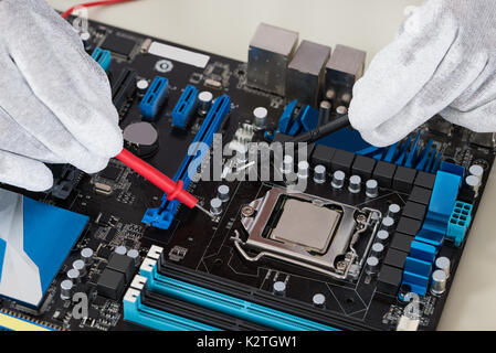Close-up Of Person Hands Checking Motherboard With Multimeter Stock Photo