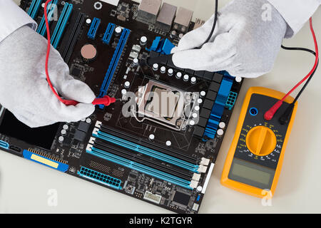 Close-up Of Person Hands Checking Motherboard With Multimeter Stock Photo