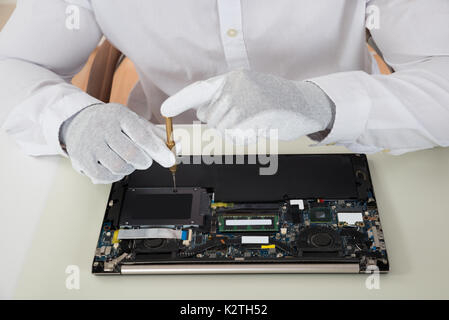 Close-up Of Technician Repairing Laptop At Desk Stock Photo