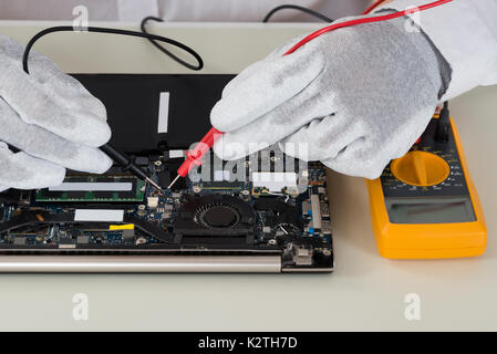 Close-up Of Person Hands Testing Laptop Motherboard Using Multimeter Stock Photo