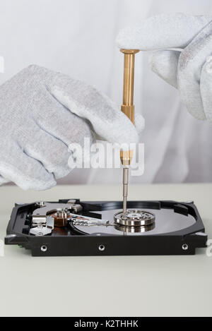 Close-up Of Person Hands Repairing Harddisk Using Screwdriver At Desk Stock Photo