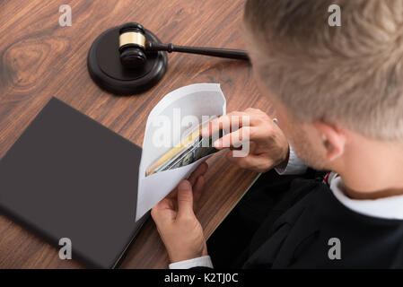 Close-up Of Judge Looking At Money At Desk In Courtroom Stock Photo
