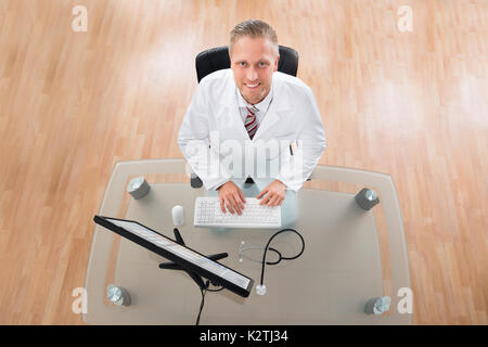Happy Young Doctor Working On Computer At Desk Stock Photo