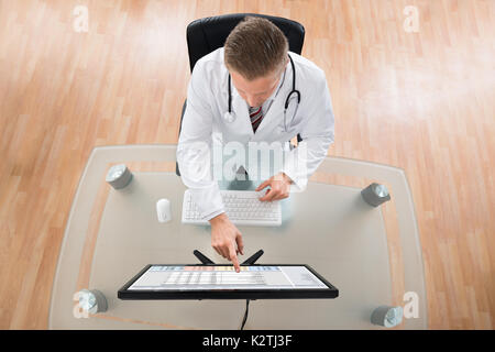 Young Doctor With Stethoscope Using Computer At Desk Stock Photo