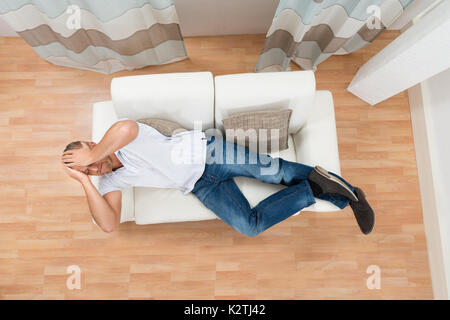 Young Man Lying On Sofa Having Headache Stock Photo