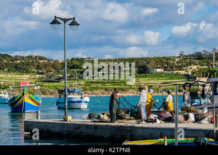 Fishermen back from sea, sorting out their catch and nets on a quay at Marsaxlokk fishing village, Malta, Mediterranean Stock Photo