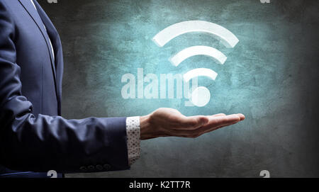 Businessman presents big virtual wifi icon. Stock Photo