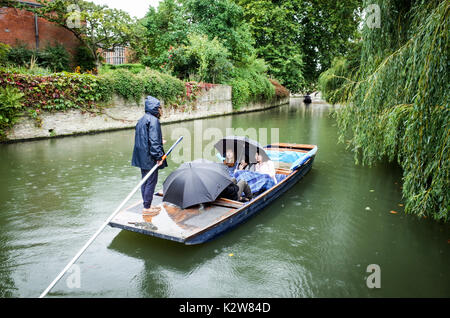 Punting in the Rain. Wet Weather Punting, Tourists take guided punts on the River Cam in rain, in Cambridge UK