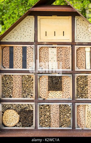 Man-made insect hotel in a green forest. A structure created from natural materials intended to provide shelter and conservation for insects. Stock Photo