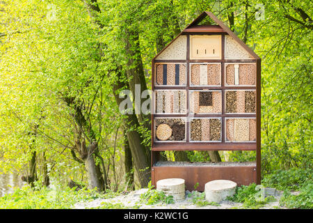 Man-made insect hotel in a green forest. A structure created from natural materials intended to provide shelter and conservation for insects. Stock Photo