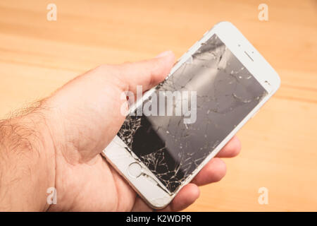 Paris, FRANCE - August 26, 2017: A man holds in his hand an iphone 6S of Apple Inc. whose screen is broken as a result of a violent fall Stock Photo