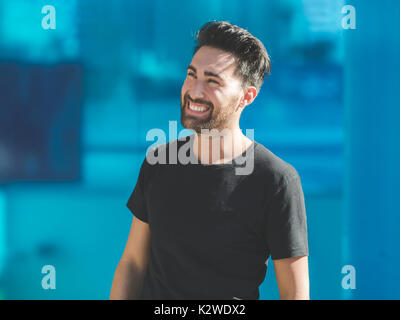Portrait of young man laughing on blue background Stock Photo