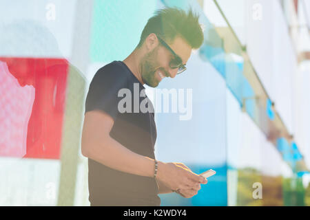 Profile portrait of laughing man in sunglasses using mobile outside Stock Photo