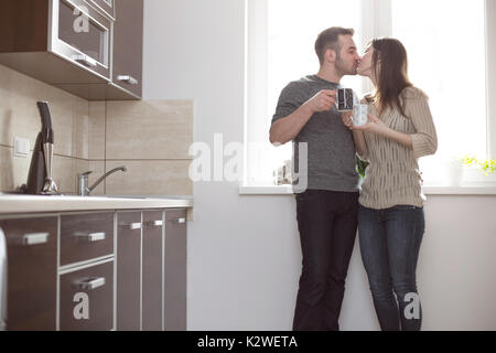 Young married people kissing in kitchen Stock Photo