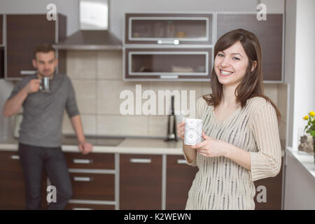 Smiling woman in kitchen with blurred man Stock Photo