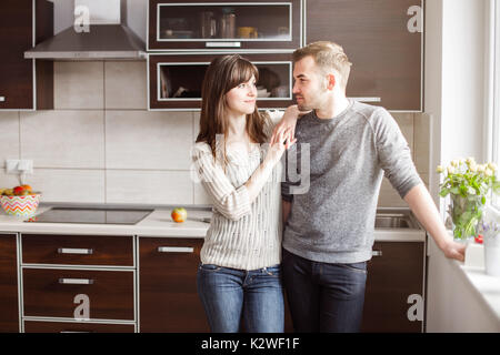 Young couple standing in kitchen in sunshine Stock Photo