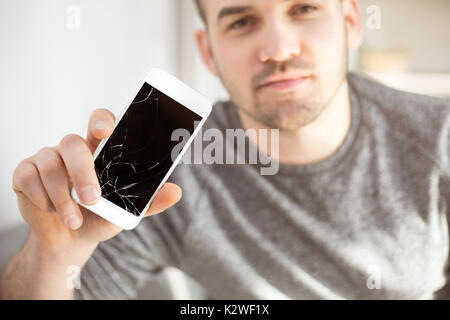 Sad man showing crashed mobile phone with touch screen Stock Photo