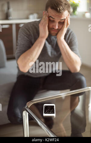 Worried man looking at broken smart phone Stock Photo