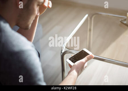 Woeful man holding damaged smart phone Stock Photo