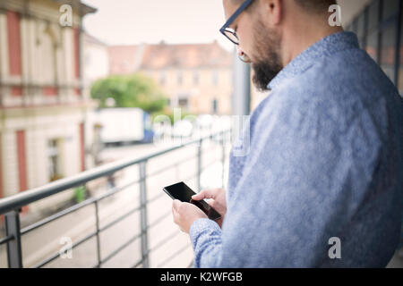 Man using smart phone and standing at terrace. Stock Photo