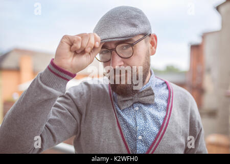 Bearded man wearing stylish cap, glasses and bow tie Stock Photo