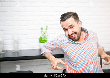 Smiling carefree man pointing fingers at camera. He is wearing casual checkered shirt. Stock Photo