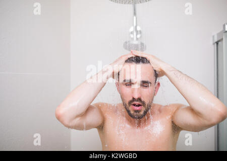 Sexy and muscular young wet male taking a shower in the nude Stock