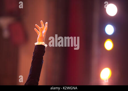 emotions, dramatic art, illumination concept. raised up male hand in full of emotions gesture in front of background of theater and spotlights in diff Stock Photo