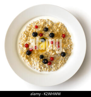 White bowl of oats porridge with chia seeds, berries, butte, brown sugar and milk solated on white from above. Stock Photo