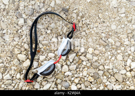 Swimming goggles on pebble beach from above. Stock Photo