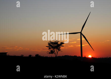 A solitary Wind Turbine silhouetted against a dramatic sunset sky ...