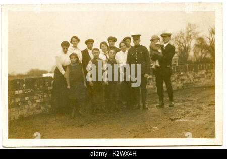 @ 1915, historical photo postcard from Britain, showing a young male soldier in uniform proudly posing with his extended family before heaiding off to fight in WW1.
