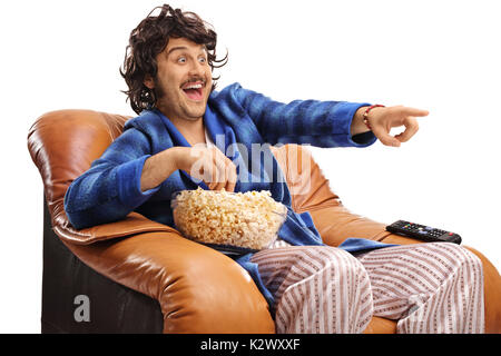 Retro guy seated in an armchair watching television and laughing isolated on white background Stock Photo