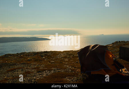 Tent on barren ground high above the Atlantic ocean with icebergs in the mist, St Anthony, Great Northern Peninsula, Newfoundland, Canada Stock Photo