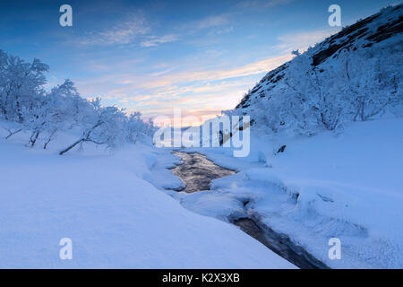 Sunrise on the frozen river and forest, Abisko, Kiruna Municipality, Norrbotten County, Lapland, Sweden Stock Photo