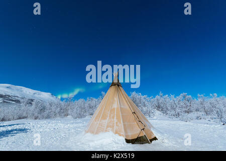 Isolated Sami tent in the snow under Northern Lights, Abisko, Kiruna Municipality, Norrbotten County, Lapland, Sweden Stock Photo