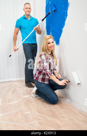 Happy Young Couple Panting Wall Of Home Stock Photo