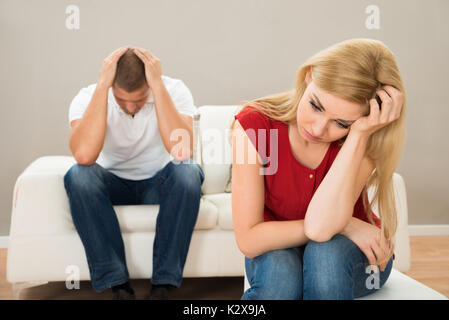 Young Man On Sofa Looking At Stressed Woman Stock Photo