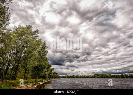 Heavy clouds in the sky over the Dnieper river announce the incoming of a summer storm Stock Photo